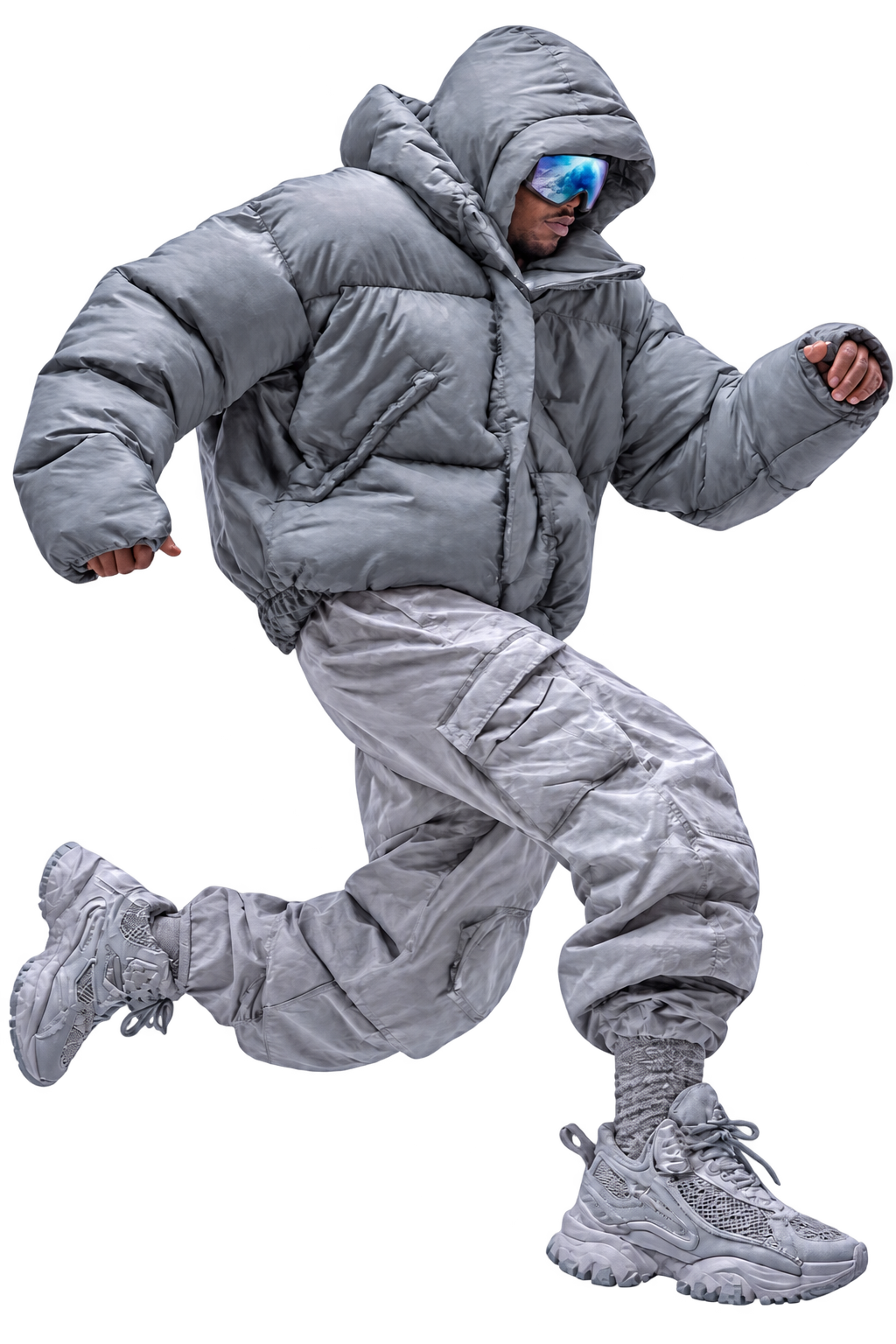 Model wearing mirrored ski goggles, a grey oversized puffer and silver cargo trousers leaping forward